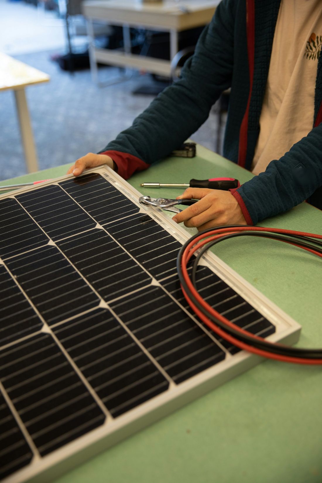 Technician tightening the frame of a solar panel with wiring nearby